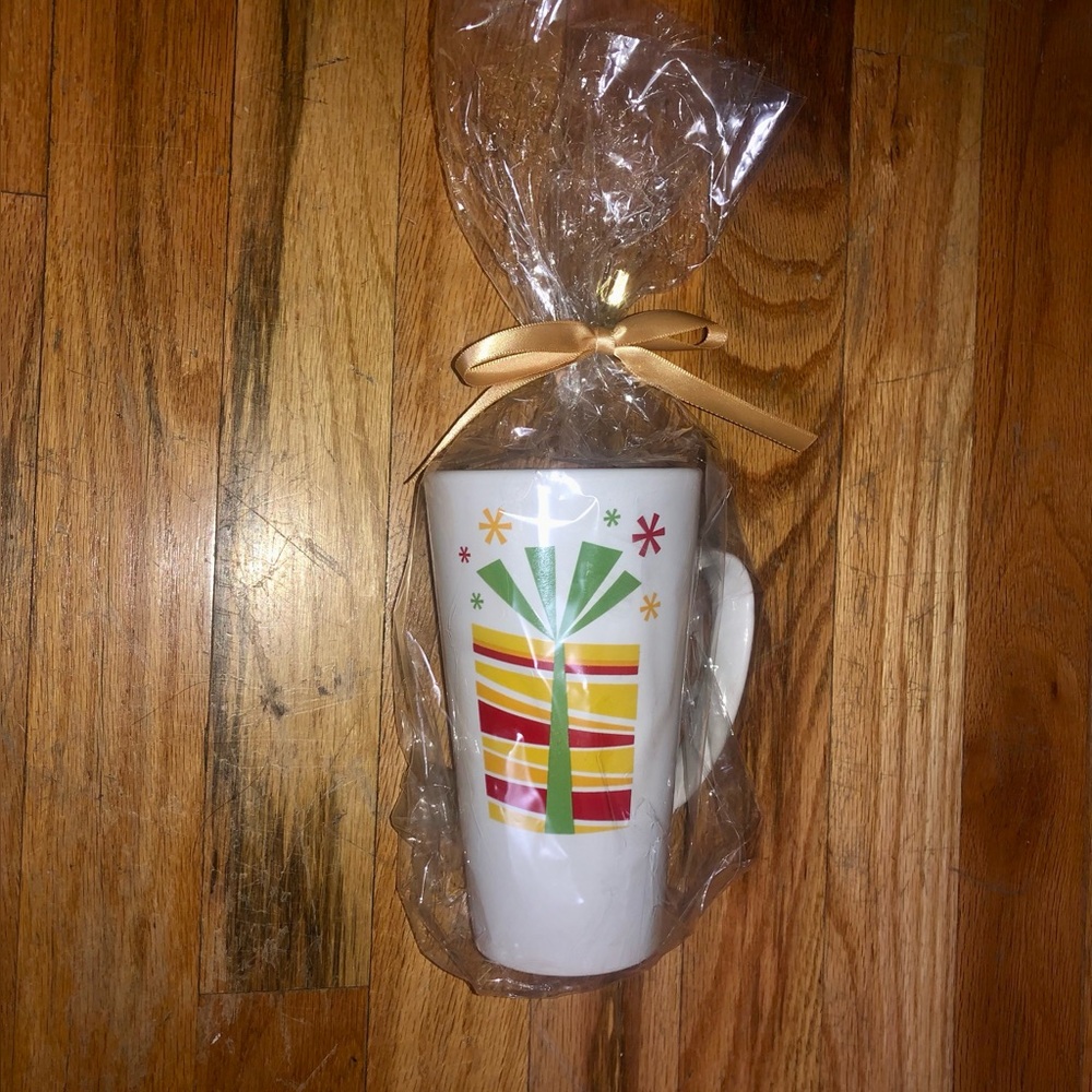 Present ceramic white mug with yellow, red, orange and green gift